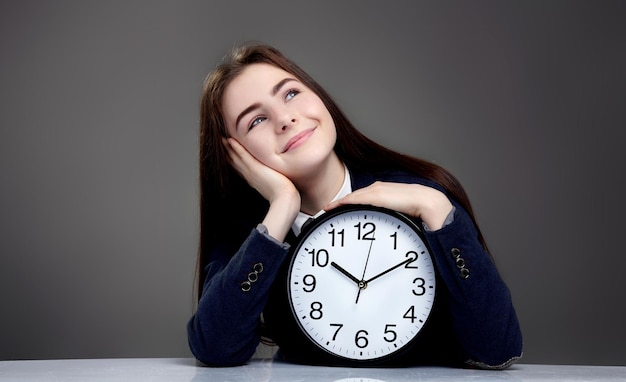 Portrait de belle jeune fille assise avec horloge