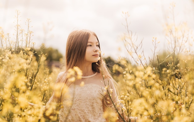 Portrait d'une belle jeune fille aux cheveux longs sur fond de fleurs de colza. Jeunesse et nature