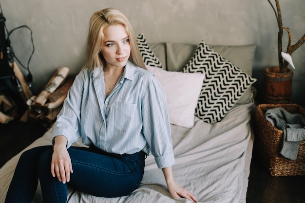 portrait d'une belle jeune fille blonde au lit le matin à la maison dans un intérieur scandinave bonjour style de vie