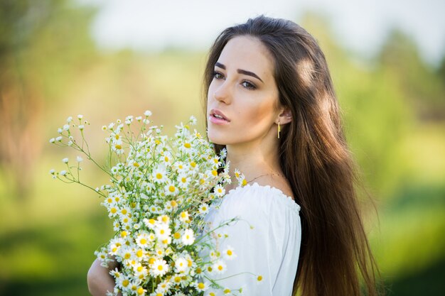 Portrait d'une belle jeune fille avec bouquet, à l'extérieur, sur le terrain