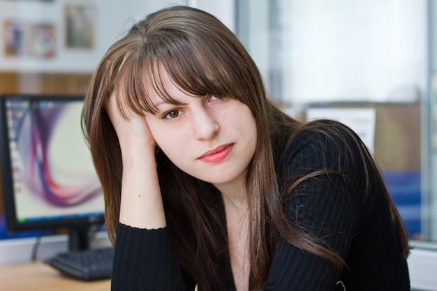 Portrait d'une belle jeune fille brune au bureau