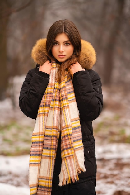 Portrait de la belle jeune fille brune en manteau d'hiver avec capuche en fourrure et écharpe chaude.