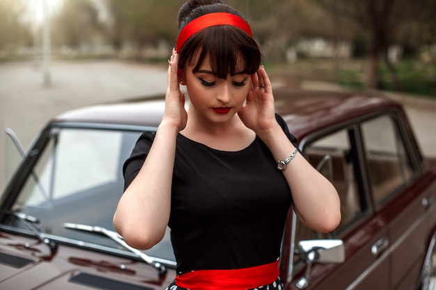 Portrait d&#39;une belle jeune fille caucasienne dans une robe vintage noire, posant près d&#39;une voiture vintage