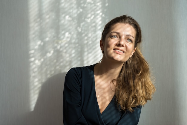 Portrait d'une belle jeune fille dans une pièce sur fond de mur gris avec des ombres