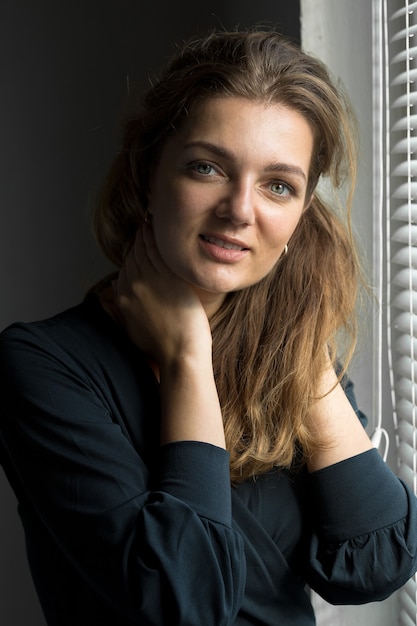 Portrait d'une belle jeune fille dans une pièce sur fond de mur gris avec des ombres