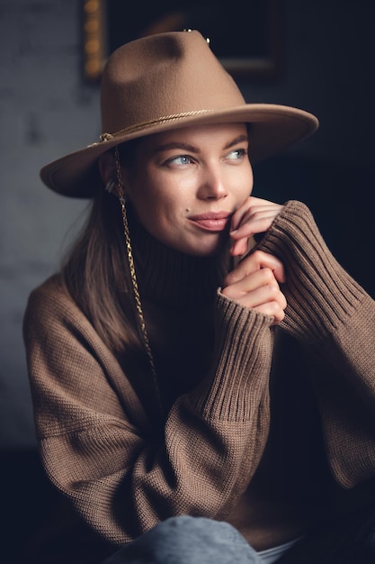 Portrait d'une belle jeune fille dans un pull marron et un chapeau à bord