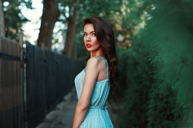 Portrait d'une belle jeune fille dans une robe bleue sur une promenade