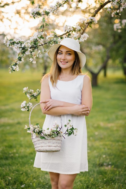 Portrait d'une belle jeune fille dans un verger de pommiers en fleurs au printemps