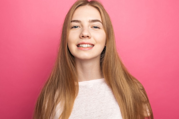 Portrait d'une belle jeune fille debout sur un mur rose