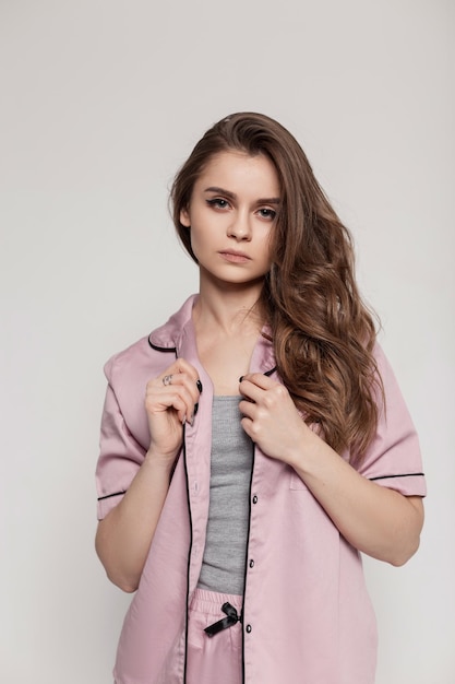 Portrait d'une belle jeune fille élégante avec une coiffure en pyjama de nuit en soie rose en studio Modèle jolie fille avec un visage mignon