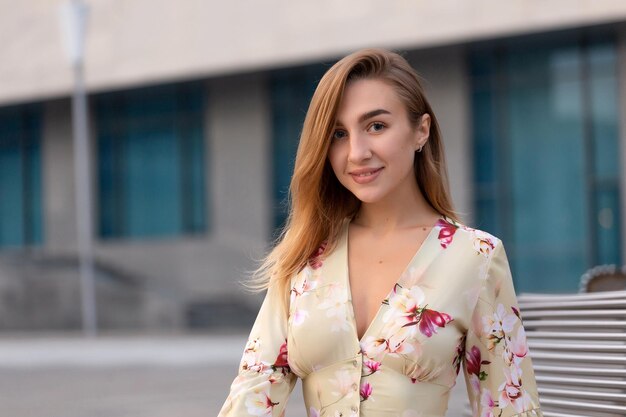 Portrait d'une belle jeune fille sur fond de centre d'affaires bleu vêtue d'une robe beige d'été