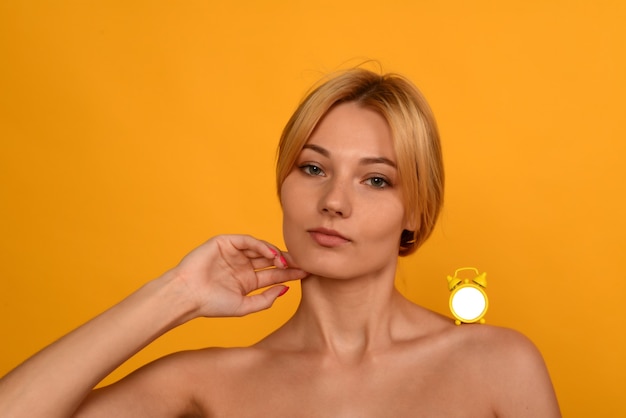 Portrait d'une belle jeune fille avec l'horloge sur l'épaule. Le concept de vieillissement. Le temps et la jeunesse ne sont pas éternels