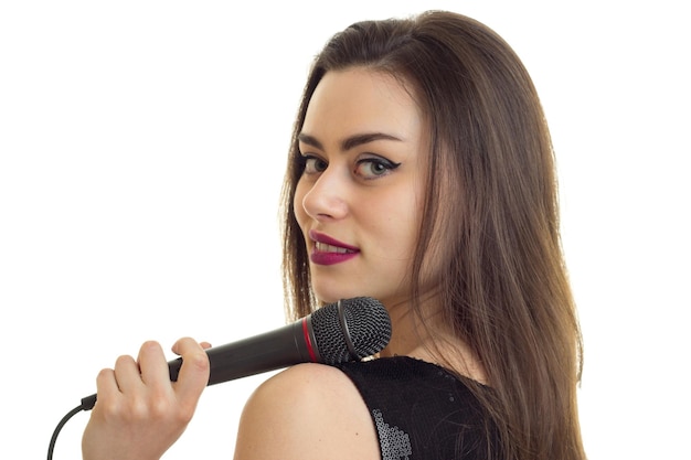 Portrait d'une belle jeune fille qui garde le microphone et le gros plan souriant