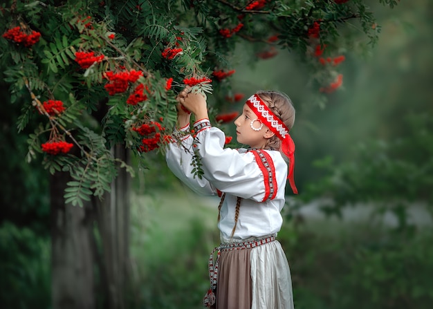 Portrait d'une belle jeune fille en robe folklorique près d'un arbre Rowan