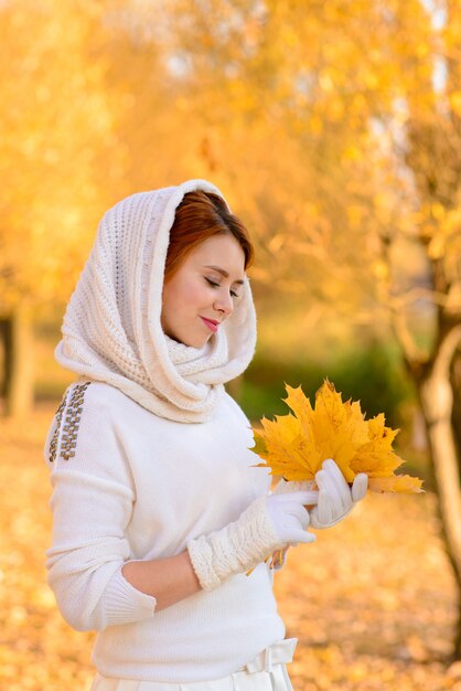 Portrait d'une belle jeune fille rousse avec des fleurs sont attrayantes dans une robe blanche