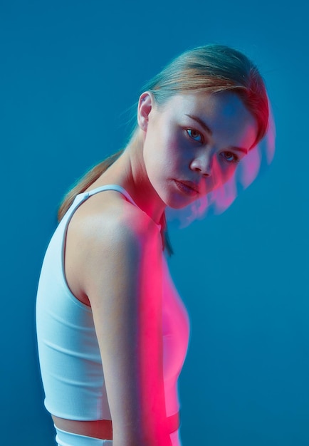 Portrait d'une belle jeune fille en uniforme de sport blanc sur fond bleu une fille avec elle