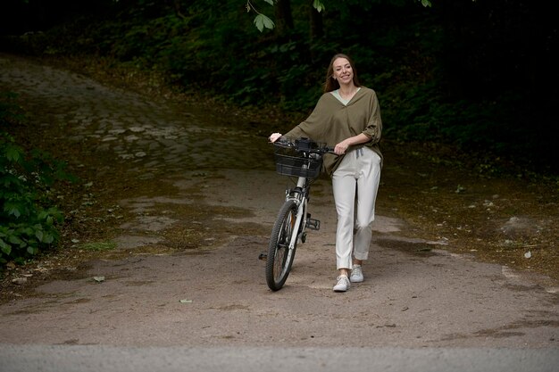 Un portrait d'une belle jeune fille avec un vélo dans le parc