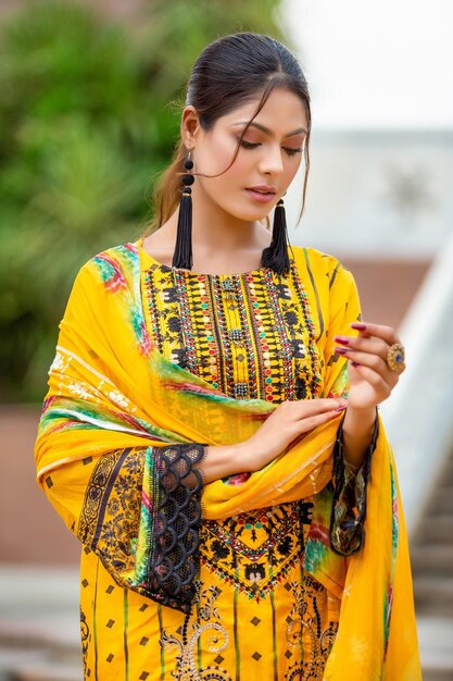 Portrait de belle jeune fille vêtue d'une robe Desi jaune pour une séance photo de mode dans un jardin