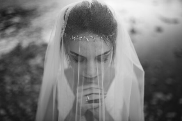 Portrait d'une belle jeune mariée. La jeune fille s'est réfugiée sous un voile.