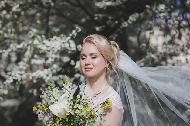 Portrait d'une belle mariée blonde avec des fleurs en fleur spring park