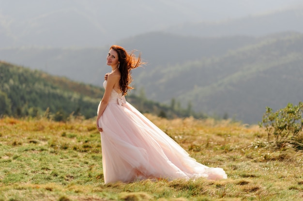 Portrait d'une belle mariée sur fond de montagnes d'automne. Le vent souffle ses cheveux. Cérémonie de mariage au sommet de la montagne. Espace libre.