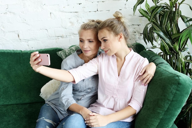 Portrait d'une belle mère mature et de sa fille faisant un selfie à l'aide d'un téléphone intelligent et souriant à la maison et heureux