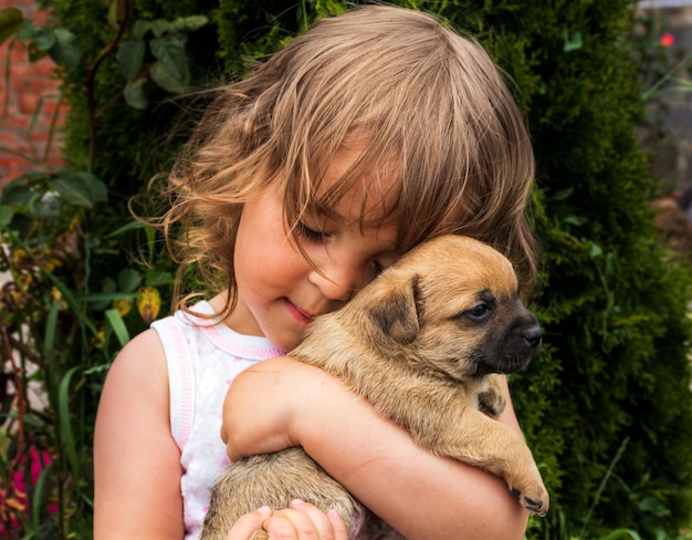 Portrait d'une belle petite fille aux cheveux bouclés avec un chiot