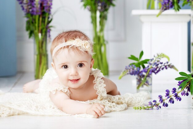 Portrait d'une belle petite fille aux fleurs violettes. Douce fille souriante allongée sur le ventre