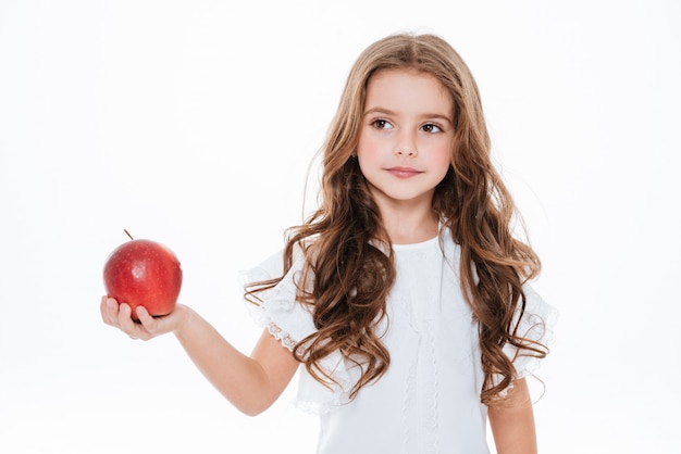 Portrait de la belle petite fille bouclée tenant la pomme rouge