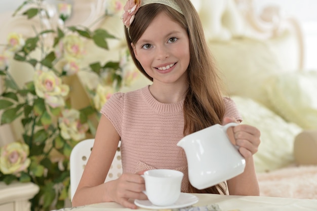 Portrait d'une belle petite fille buvant du thé