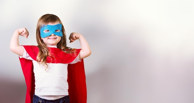 Portrait de belle petite fille en costume de super-héros sur fond de ciel