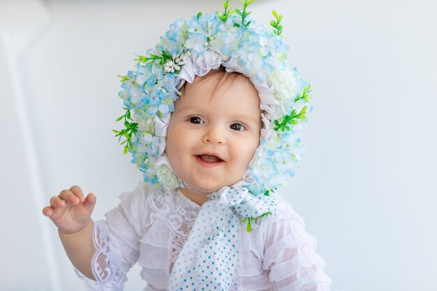 Portrait d'une belle petite fille dans une pièce lumineuse dans un chapeau fait de fleurs
