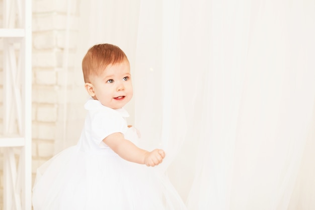 Portrait d'une belle petite fille dans une robe blanche à l'intérieur