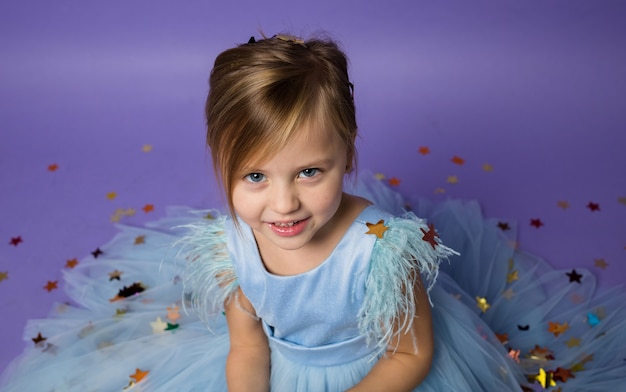 Portrait d'une belle petite fille dans une robe bleue festive sur violet