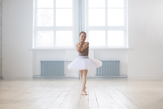 Portrait d'une belle petite fille en robe tutu debout dans une pose de ballet pendant sa formation à l'école de danse