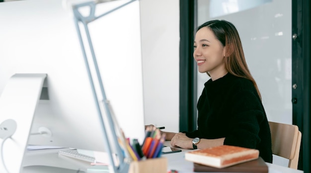 Portrait d'une belle pigiste asiatique utilisant un ordinateur de bureau au bureau à domicile