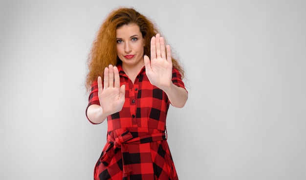 Portrait de belle rousse contrarié frustrée triste jeune femme montrant le panneau d'arrêt sur gris