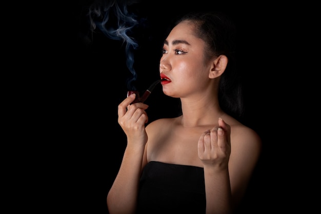 Portrait de belles jeunes femmes d'Asie avec un tabac à pipe sur le fond noir