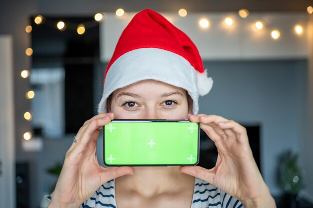 Portrait de belles jeunes femmes portent un chapeau de père Noël avec un téléphone mobile intelligent