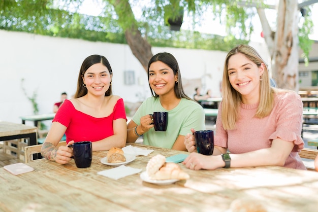 Portrait de belles meilleures amies souriantes tout en traînant ensemble dans un café. Jeunes femmes profitant d'une conversation amusante à l'extérieur