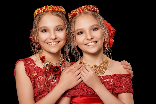 Portrait de belles petites filles en robes rouges sur fond noir