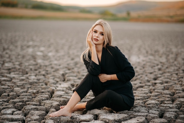 le portrait d'une blonde assise sur un lac asséché