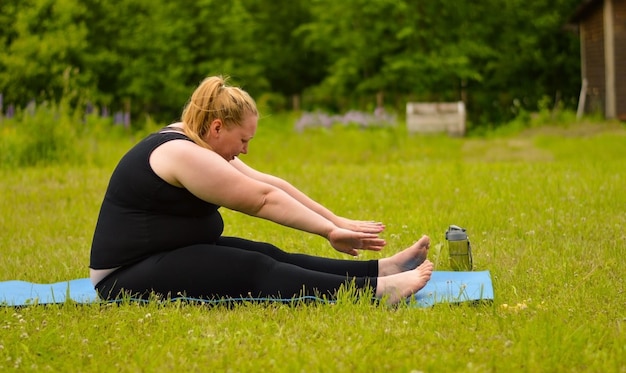 Portrait de bonheur plus taille femme pratiquant le yoga à l'extérieur