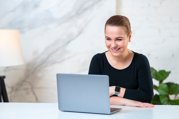 Portrait de bonne fille positive joyeuse utilise, travaille sur ordinateur