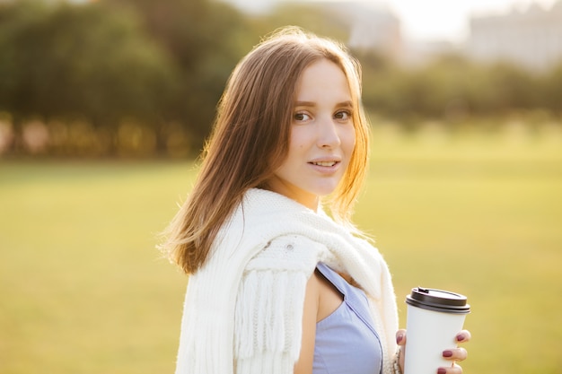 Portrait de bonne jeune femme avec un look attrayant, bénéficie de café aromatique de tasse jetable