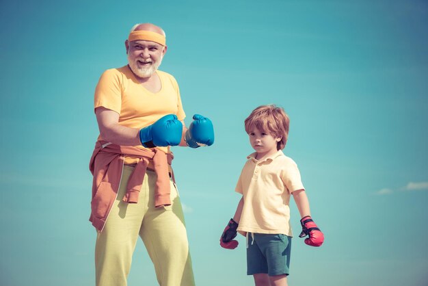 Portrait d'un boxeur senior déterminé avec petit garçon enfant sur fond de ciel bleu grand-père Boxer