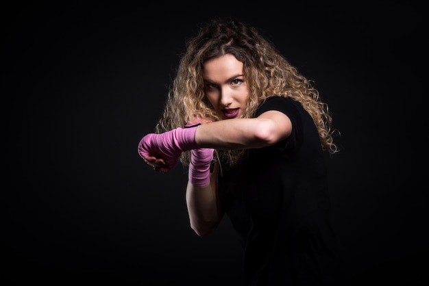 Portrait d'une boxeuse debout sur un fond noir