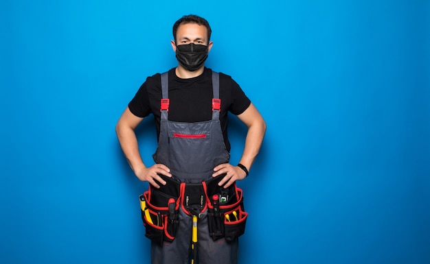 Portrait de bricoleur heureux avec masque médical avec ceinture d'outils