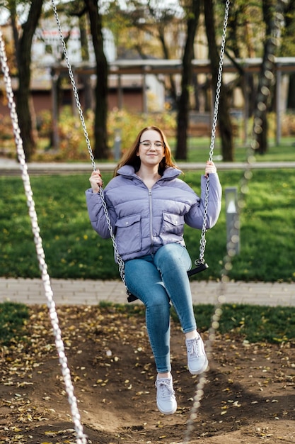 Portrait candide de la belle jeune femme sur la balançoire le jour du printemps à l'extérieur fille adolescente étudiante heureuse