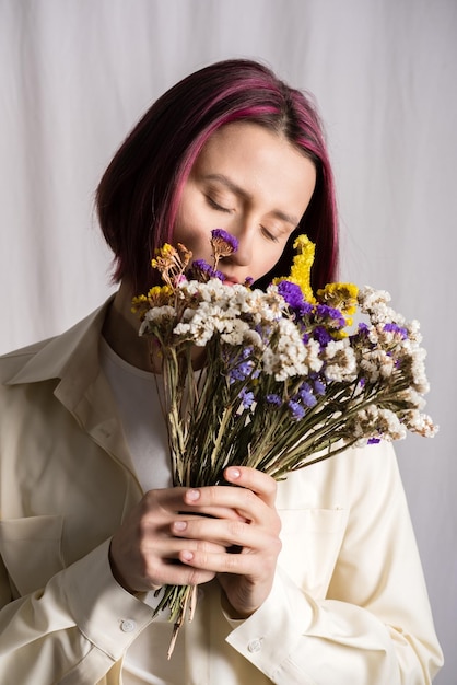 Portrait candide d'une belle jeune femme paisible aux cheveux violets avec un bouquet